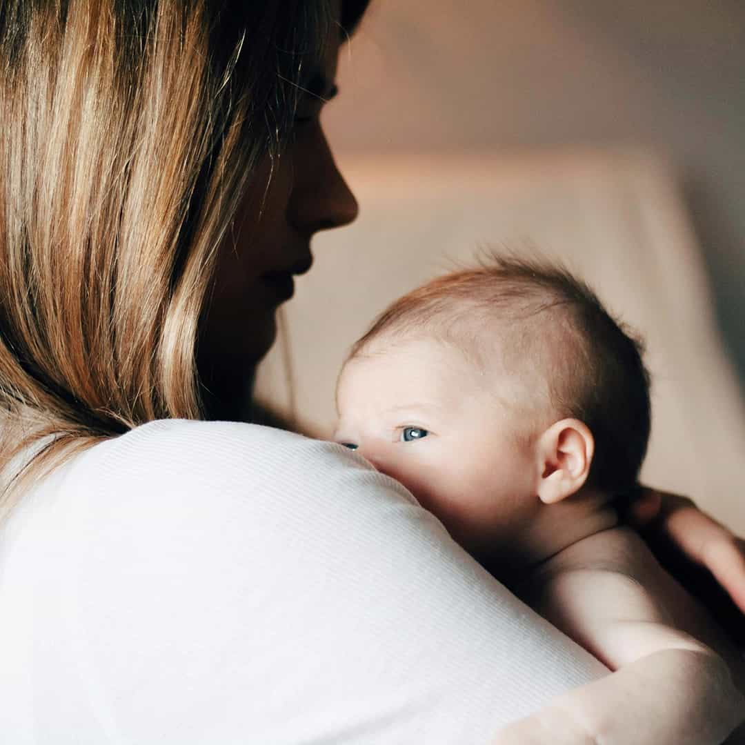 Mother cradling her newborn baby in warm light